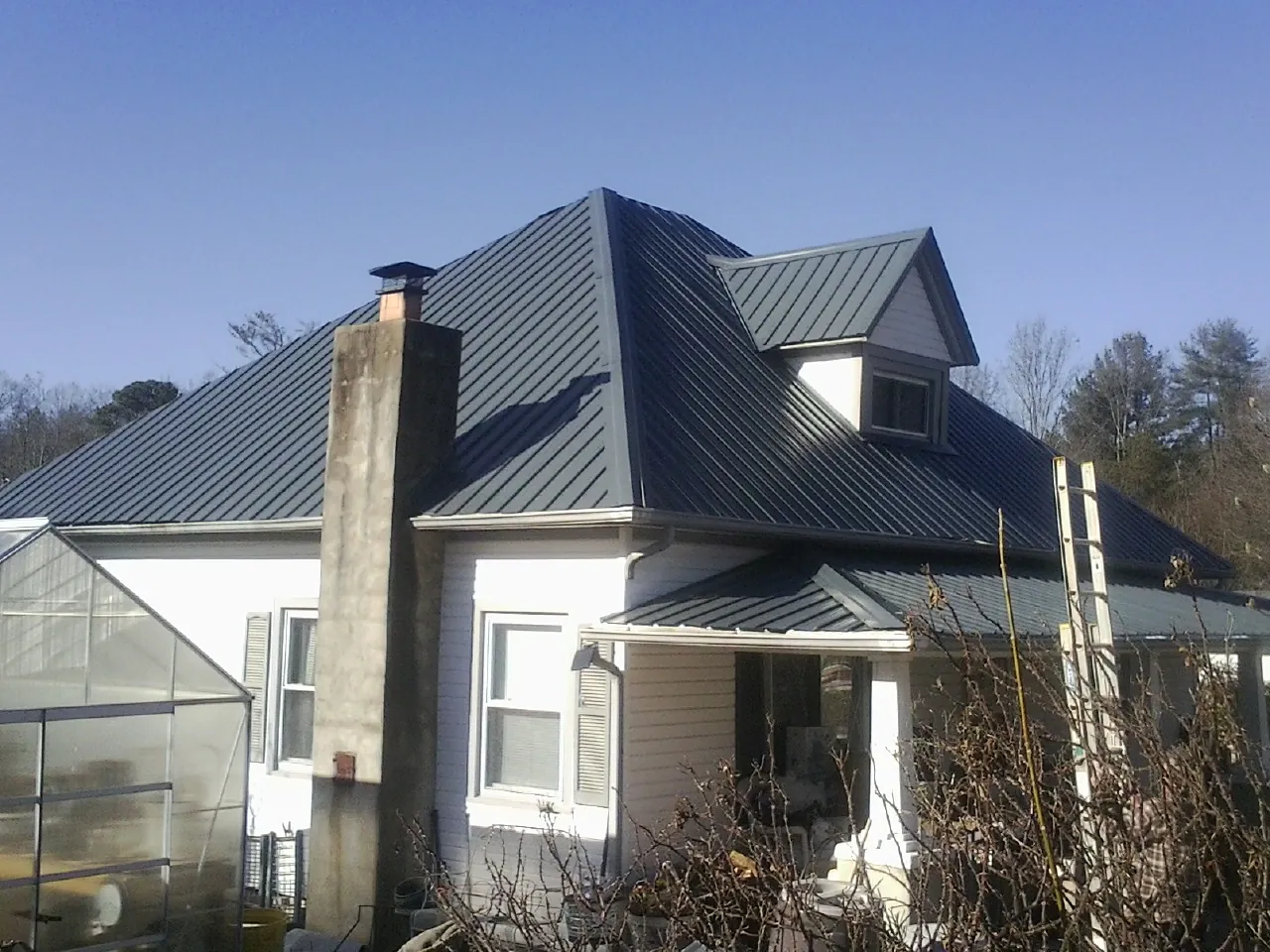 Dark blue standing seam metal roof on a white farmhouse with dormer — Slate & Tile Roof Repair by Roofing Brothers in Fountain Inn