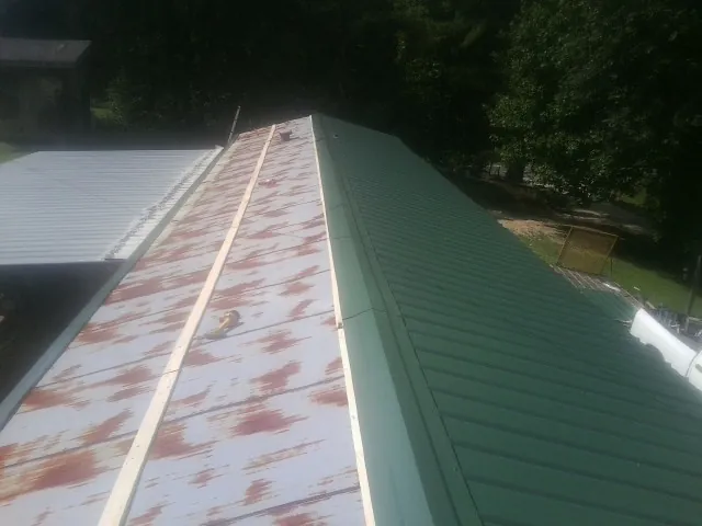 Old rusted panels beside newly installed green metal roofing — Wind Damage Roof Repair by Roofing Brothers in Fountain Inn