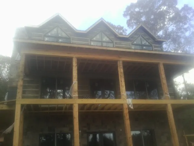 Dormers and porch framing on a large log home under construction — Roof Coating work by our crew in Fountain Inn