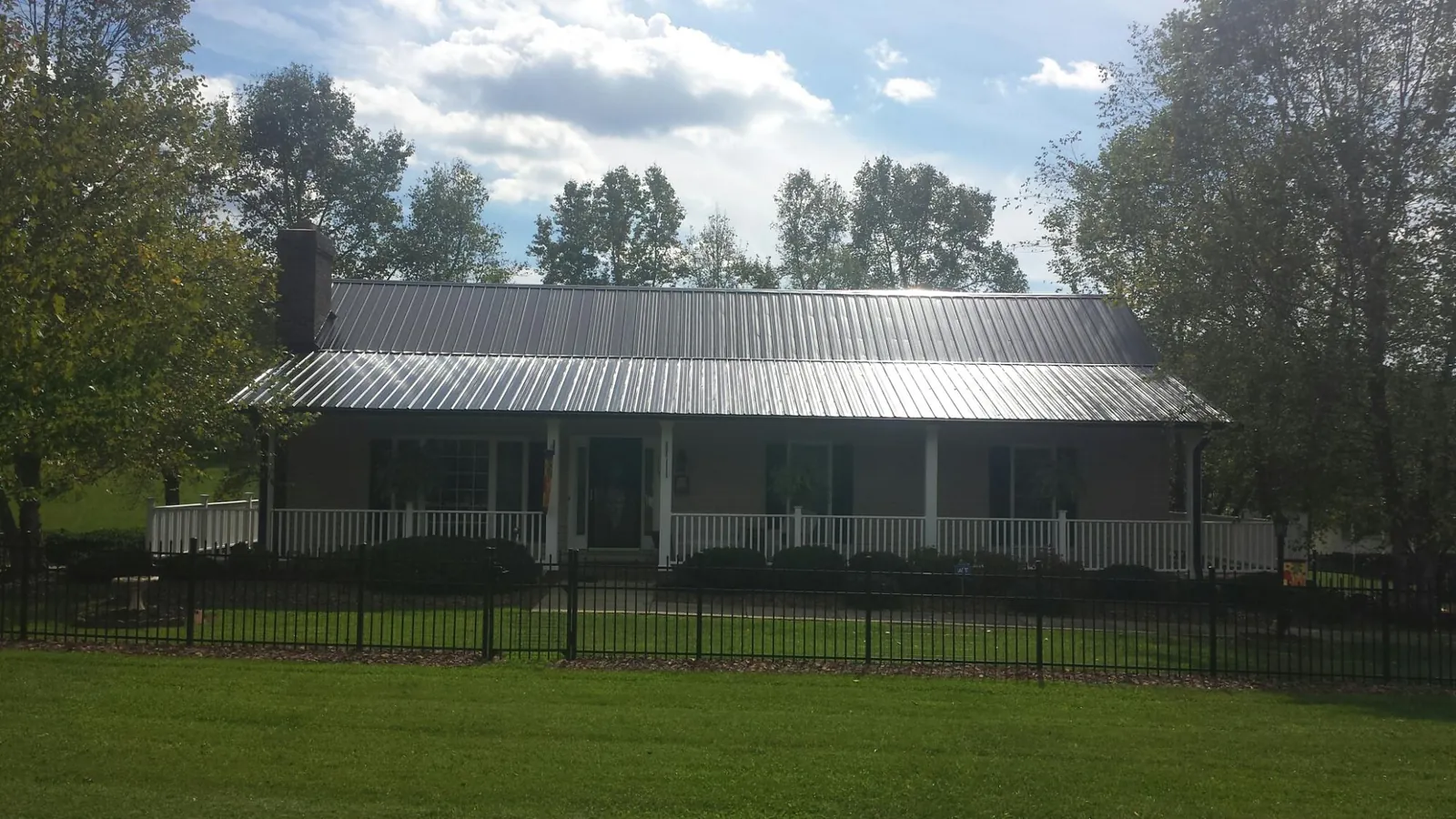 Gray metal roof on a brick ranch with a full width front porch — Gutter Guard Installation work by our crew in Fountain Inn