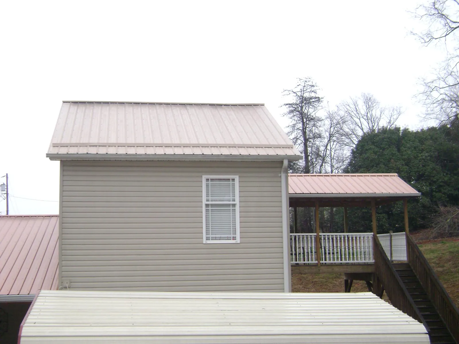 Tan metal roofs on a two story addition and attached porch, from a Roof Replacement job in Fountain Inn
