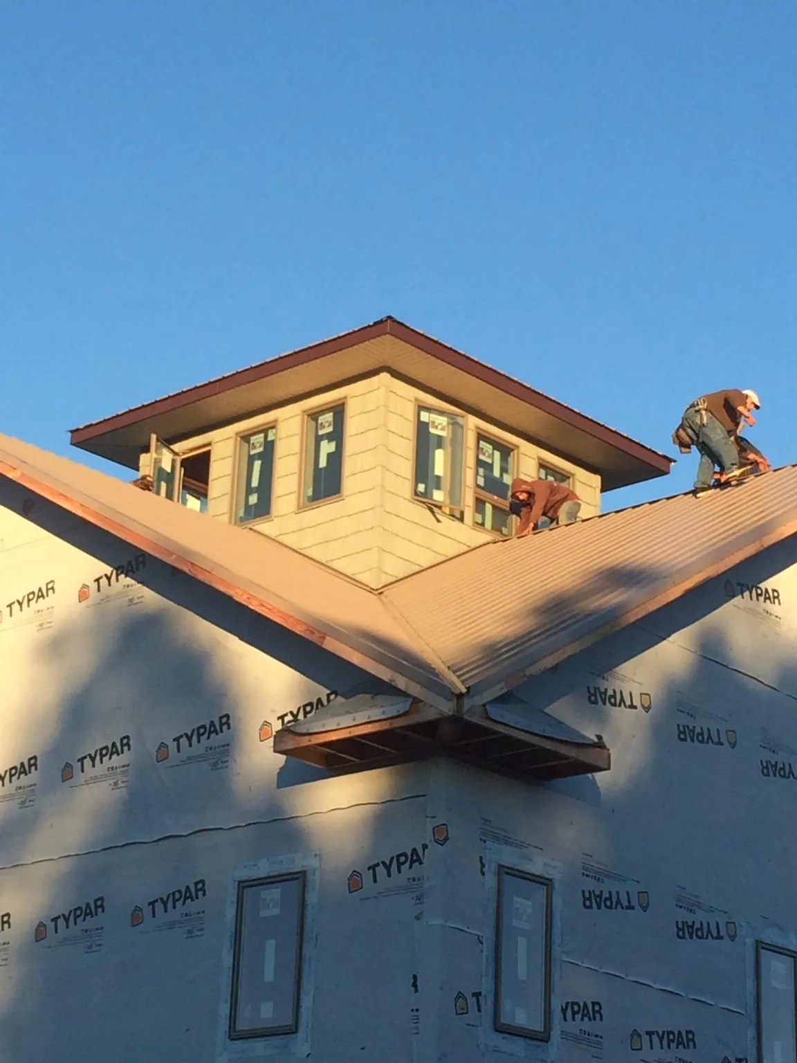 Roofers working around a rooftop cupola on a new metal roof at sunset — Roof Waterproofing in Fountain Inn by Roofing Brothers